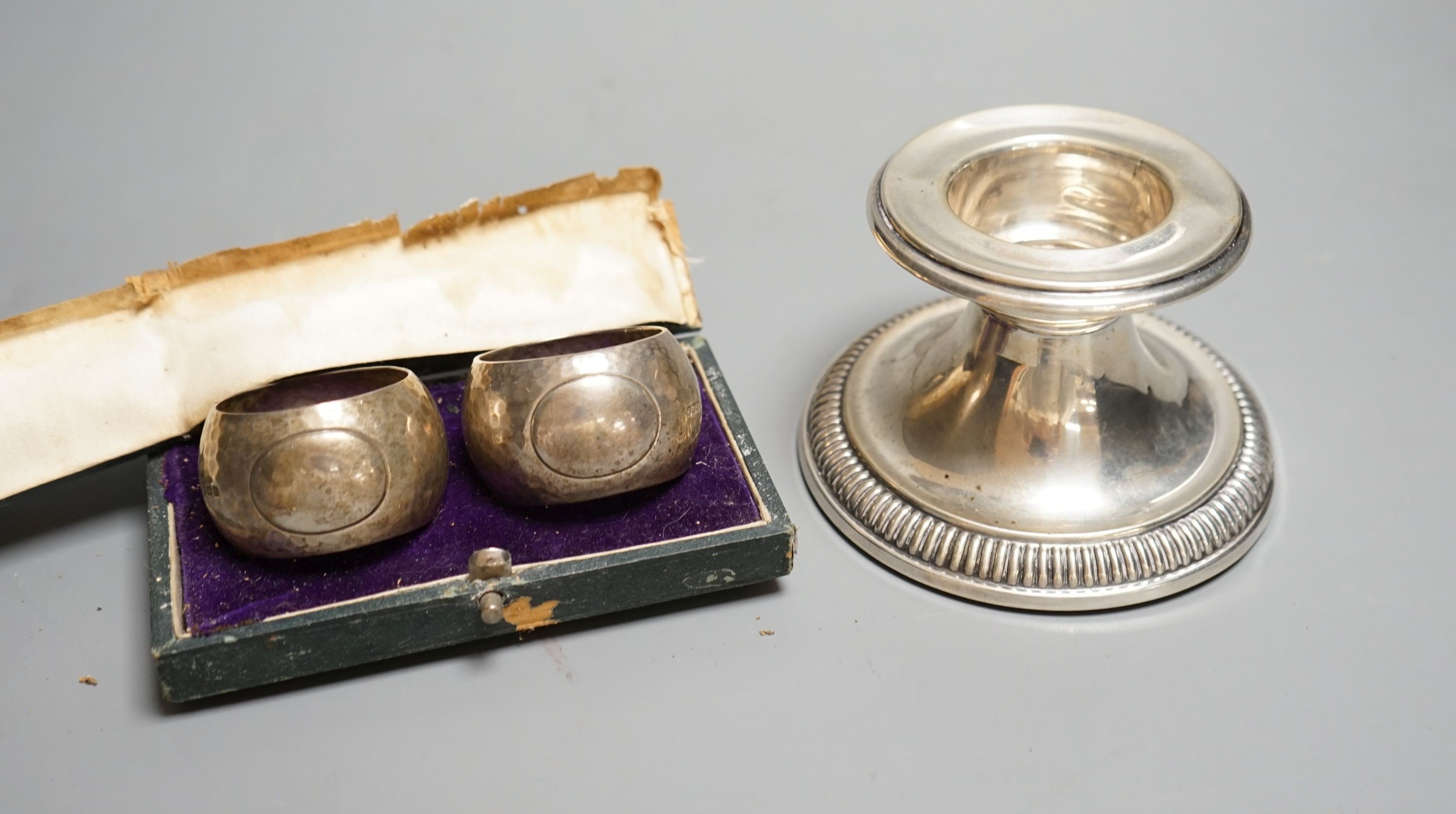 A German white metal dwarf candlestick and a cased pair of silver napkin rings by Walker & Hall.